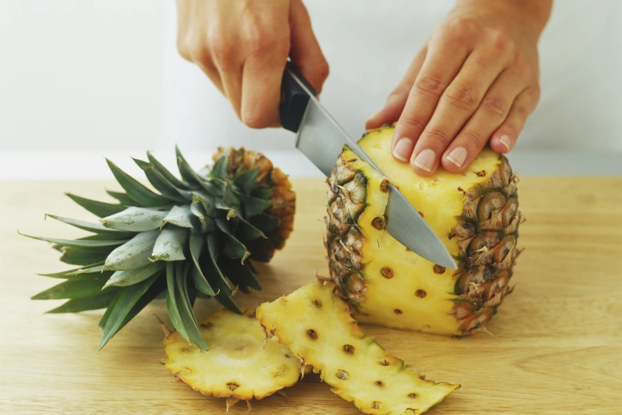 Baasje snijdt gevaarlijke stekelige schil van de ananas af. 